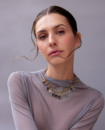 Model wearing the Katerina Psoma Gemma short necklace, a gold-plated chain with square crystals in grey, peach, pink, violet and brown.