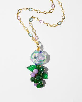 A gold chain necklace featuring a grapevine pendant with green and lavender beads, green enamel leaves, and a faceted iridescent bead at the top, displayed on a clean white background.