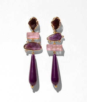 A pair of gold-tone drop earrings featuring stacked purple and pink gemstones, including teardrop-shaped beads and rectangular pink stones, set against a plain white background.