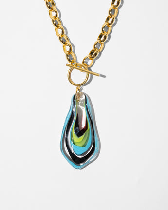 detail of Katerina Psoma Plume Murano chain Pendant made of  gold chain necklace with a toggle clasp and a teardrop-shaped pendant featuring a glossy, layered swirl of black, blue, green, and iridescent tones, set against a plain white background.