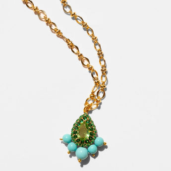 Gold necklace with a green teardrop pendant and turquoise beads on a white background